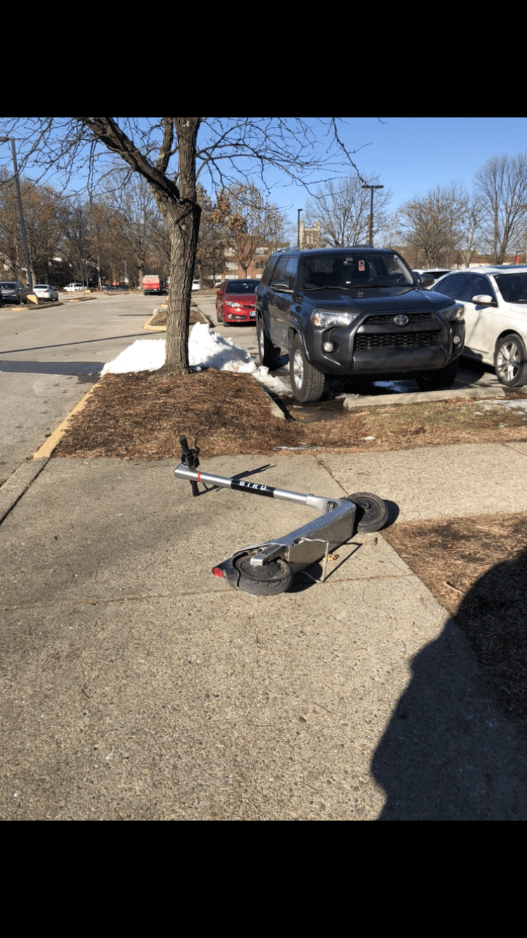 Electric scooter laying down in the middle of the sidewalk