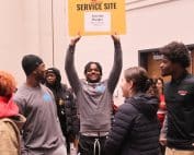 Student holding up service site sign at UofL's MLK Day of Service.